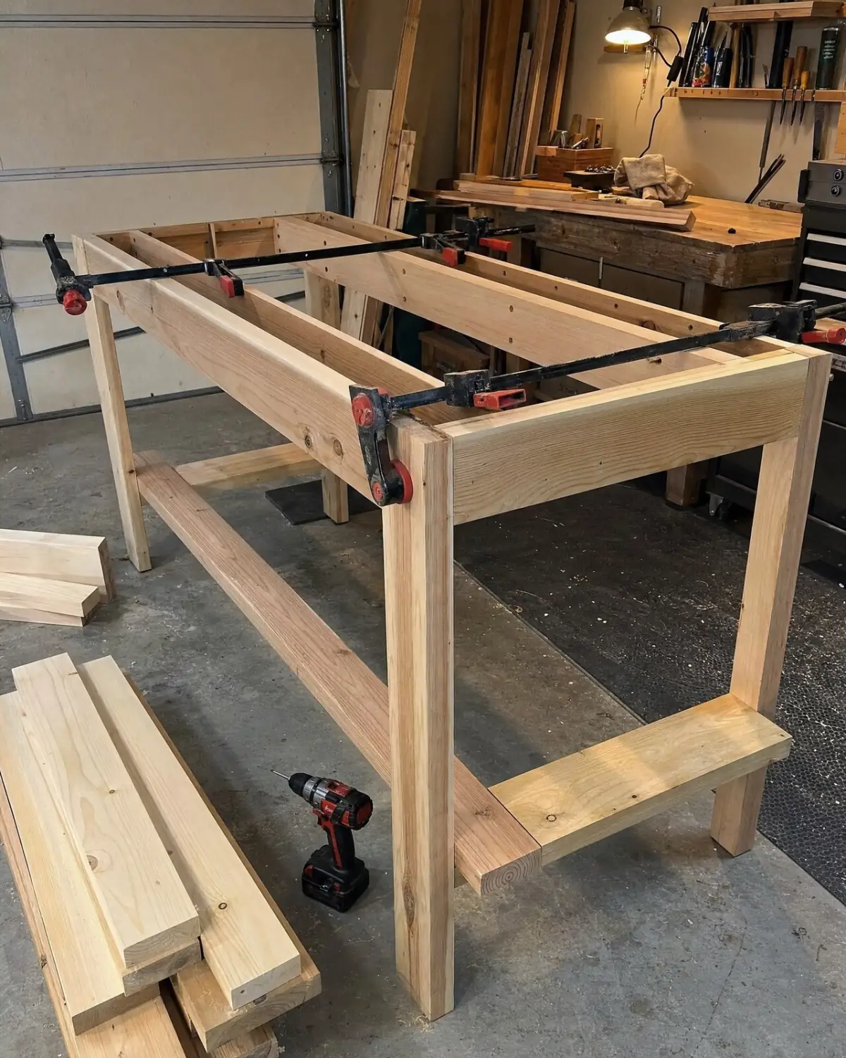 A half-built workbench frame clamped together in a garage